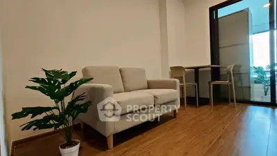 Modern living room with cozy sofa and indoor plant, featuring wooden flooring and natural light.