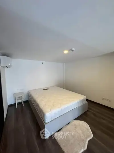 Spacious bedroom with modern design and cozy ambiance, featuring a comfortable bed and sleek flooring.