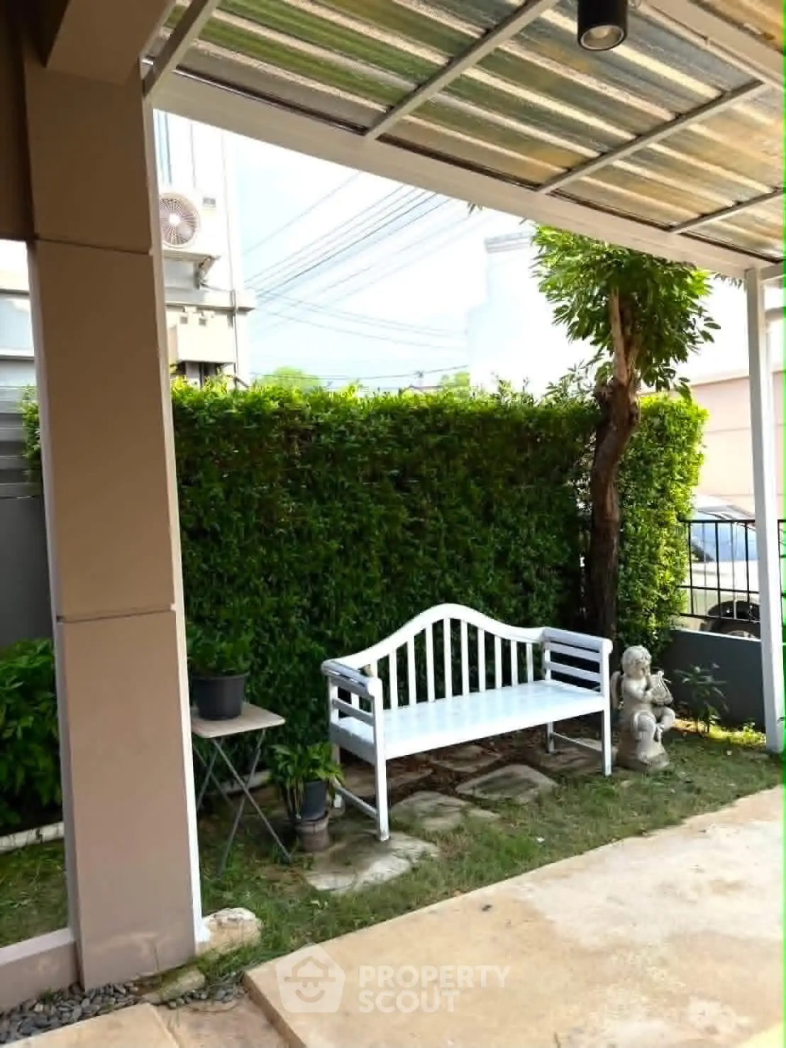 Charming garden corner with white bench and lush greenery, perfect for relaxation.