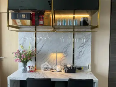 Elegant home bar with marble countertop and glass storage, featuring modern lighting and stylish decor.