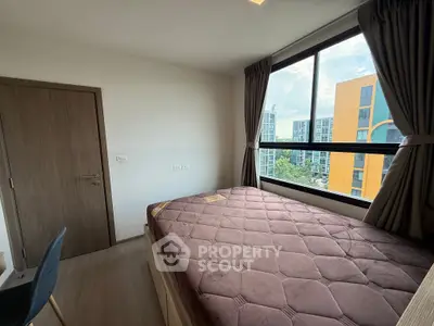 Cozy bedroom with large window offering city view in modern apartment