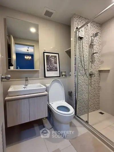 Modern bathroom with sleek shower and stylish vanity in contemporary apartment.