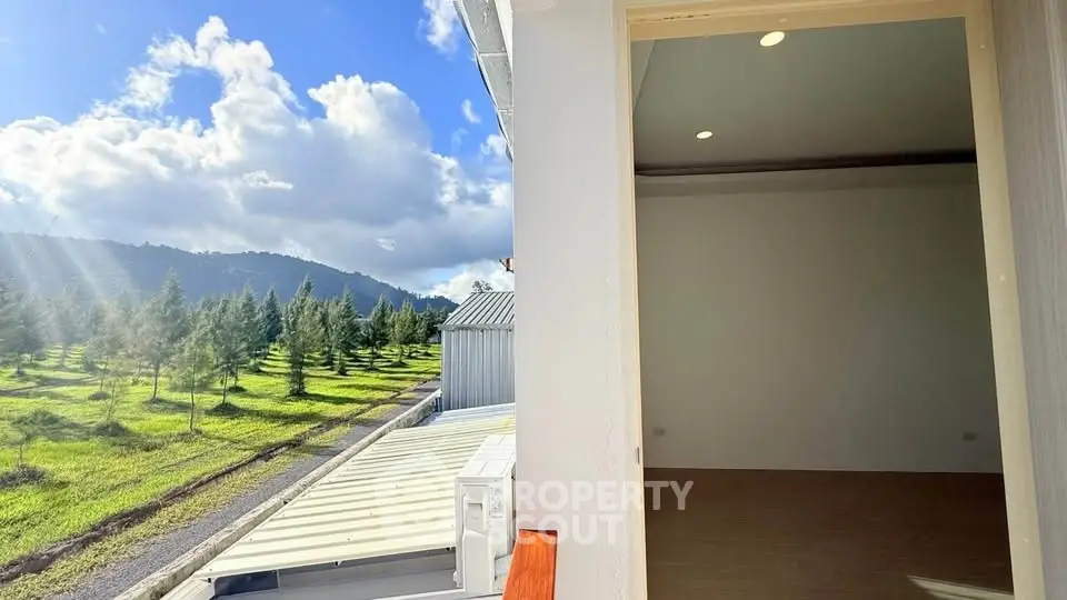 Stunning view from a modern balcony overlooking lush greenery and mountains.
