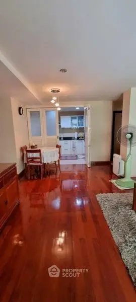 Spacious open-plan living room with wooden flooring and cozy dining area leading to a modern kitchen.
