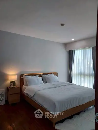 Cozy bedroom with modern decor and large window offering natural light.