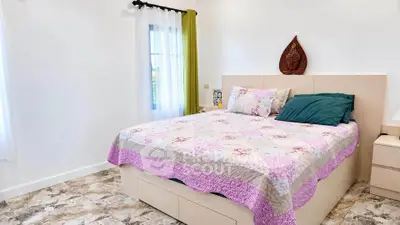 Cozy bedroom with stylish decor and natural light, featuring a comfortable bed and elegant flooring.