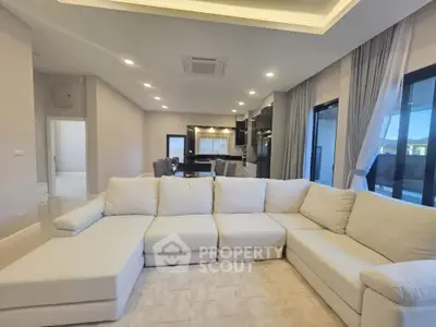 Spacious modern living room with elegant sectional sofa and open kitchen layout, perfect for entertaining.