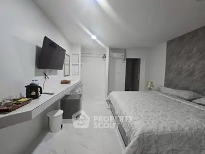 Modern bedroom with sleek design, featuring a wall-mounted TV and minimalist decor.