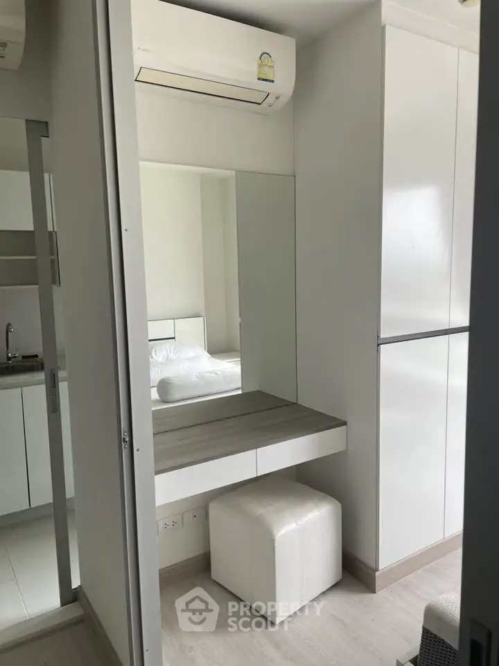 Modern bedroom with sleek white furniture and built-in air conditioning unit.