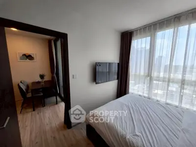 Modern bedroom with large windows and city view, adjacent to a cozy dining area.