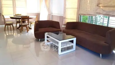Spacious living room with modern brown sofas and elegant dining area.