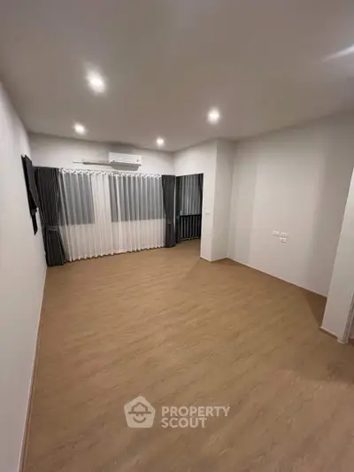 Spacious empty living room with wooden flooring and modern lighting