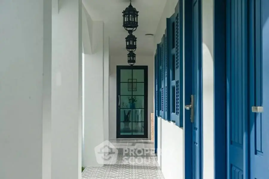 Charming corridor with blue doors and elegant hanging lanterns in a modern building.