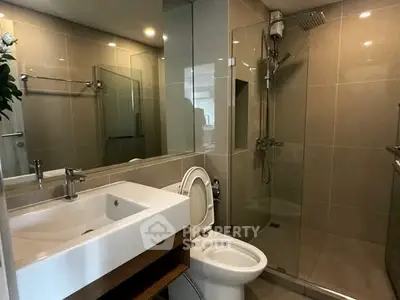 Modern bathroom with glass shower and sleek fixtures in contemporary apartment.