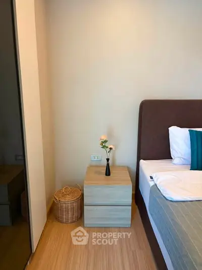 Cozy bedroom with modern decor and wooden flooring, featuring a stylish nightstand and elegant bed setup.