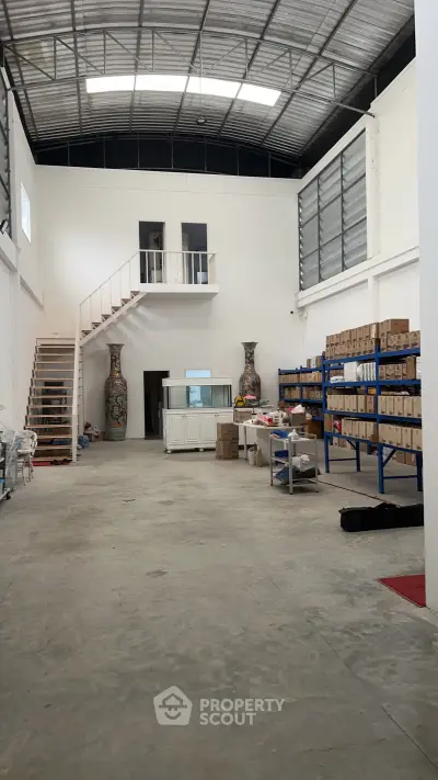 Spacious warehouse interior with high ceilings and mezzanine storage area.