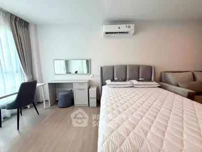 Modern studio apartment with cozy bed, stylish desk, and comfortable seating area.