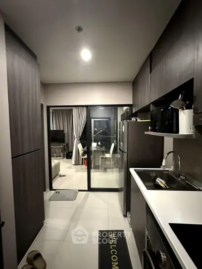 Modern kitchen with sleek cabinets and open layout leading to dining area.