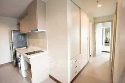 Modern apartment interior with compact kitchen and washing machine, sleek cabinetry, and bright hallway.
