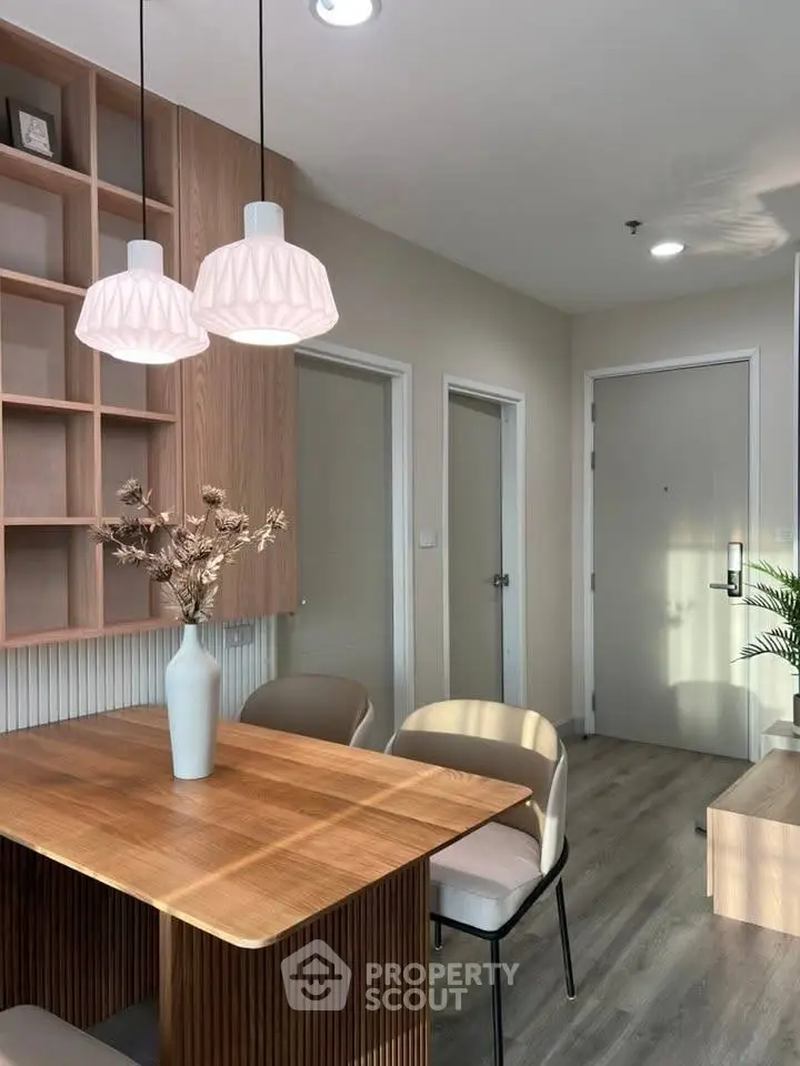 Modern dining area with wooden table and stylish pendant lights in a cozy apartment.
