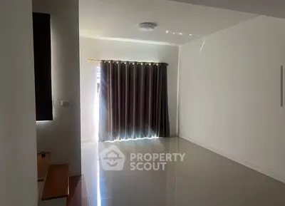 Spacious empty room with glossy tiled floor and large window with curtains.