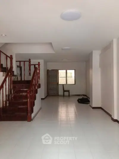 Spacious interior with elegant wooden staircase and tiled flooring, ideal for customization.