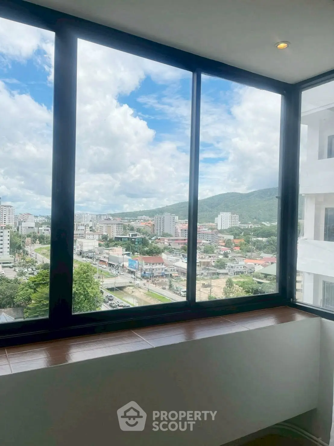Stunning cityscape view from a modern high-rise apartment window, showcasing urban living with scenic mountain backdrop.