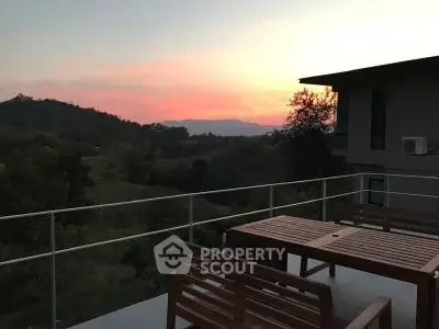 Stunning sunset view from a modern balcony with wooden furniture and scenic hills.