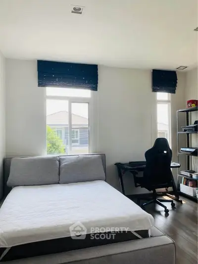 Modern bedroom with cozy bed and study area, perfect for work and relaxation.