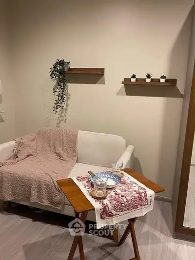 Cozy living room corner with white sofa, wooden shelves, and decorative plants.
