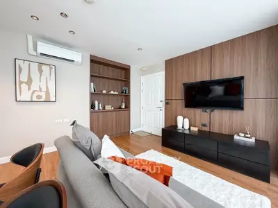 Modern living room with stylish decor, wall-mounted TV, and cozy seating area.