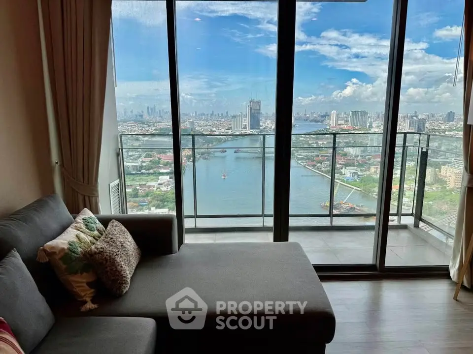 Stunning high-rise living room with panoramic city and river view from a spacious balcony.