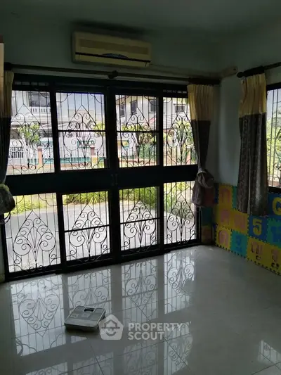 Spacious living room with large windows and decorative iron grills, offering a bright and airy atmosphere.