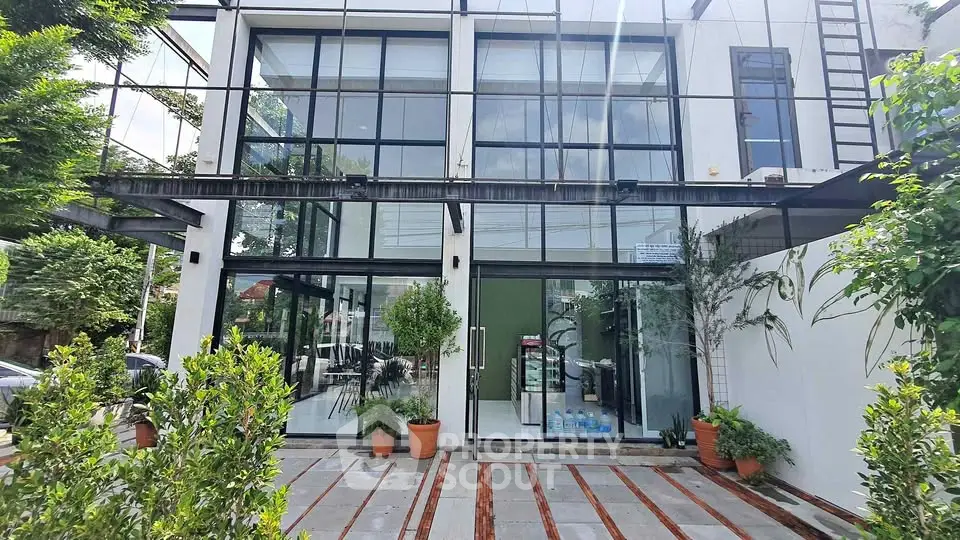Modern commercial building with large glass windows and lush greenery