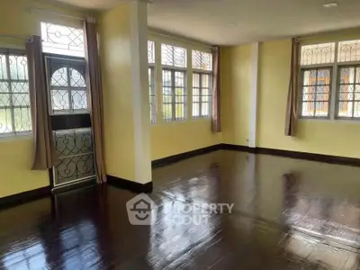 Spacious living room with polished dark wood floors and large windows for natural light.