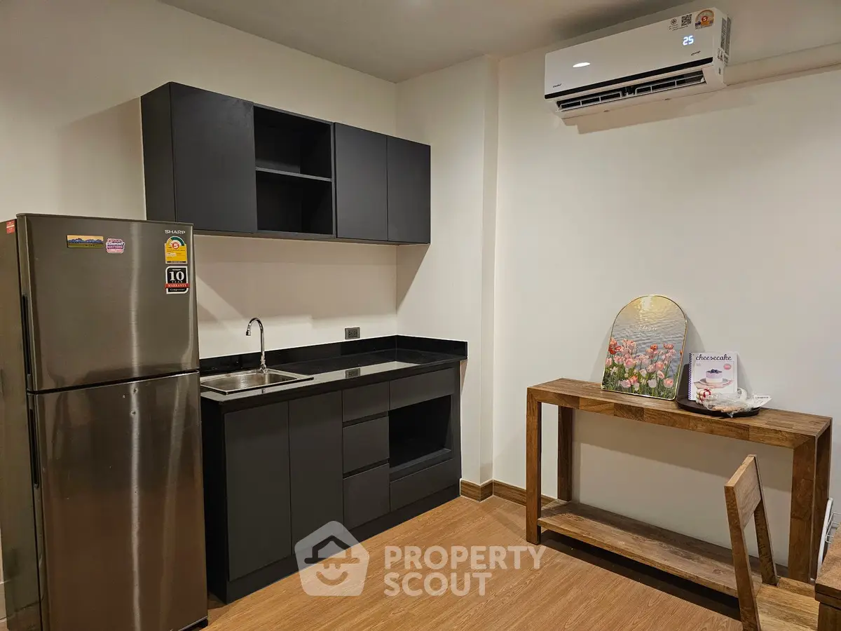 Modern kitchen with sleek black cabinets and stainless steel fridge