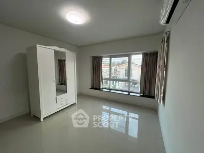 Spacious bedroom with large window and wardrobe, offering ample natural light and modern design.