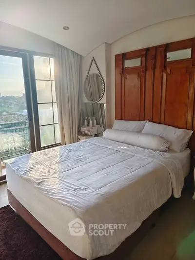 Cozy bedroom with large window and elegant decor, offering a serene view and abundant natural light.