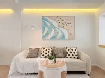 Stylish living room with cozy sofa, modern decor, and beach-themed artwork.