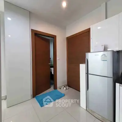 Modern kitchen with sleek white cabinets and stainless steel fridge in a cozy apartment.