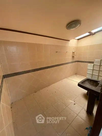 Spacious tiled bathroom with natural light and modern fixtures.