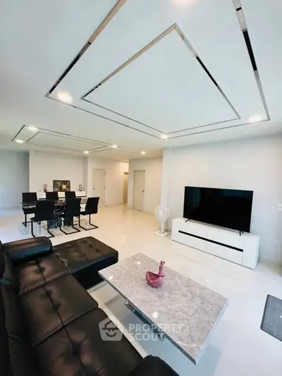 Spacious modern living room with sleek black leather sofa and elegant dining area.