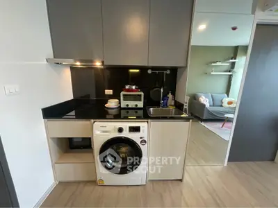 Modern compact kitchen with washing machine and cozy living room view