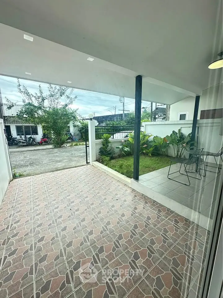 Charming covered patio with garden view and tiled flooring, perfect for outdoor relaxation.