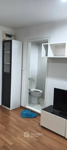 Modern apartment interior with wooden flooring and compact bathroom view.