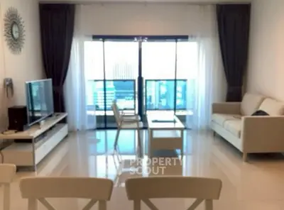 Spacious living room with modern furniture and large windows offering city views.