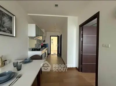 Modern kitchen with dining area in a stylish apartment, featuring sleek cabinetry and elegant tableware.