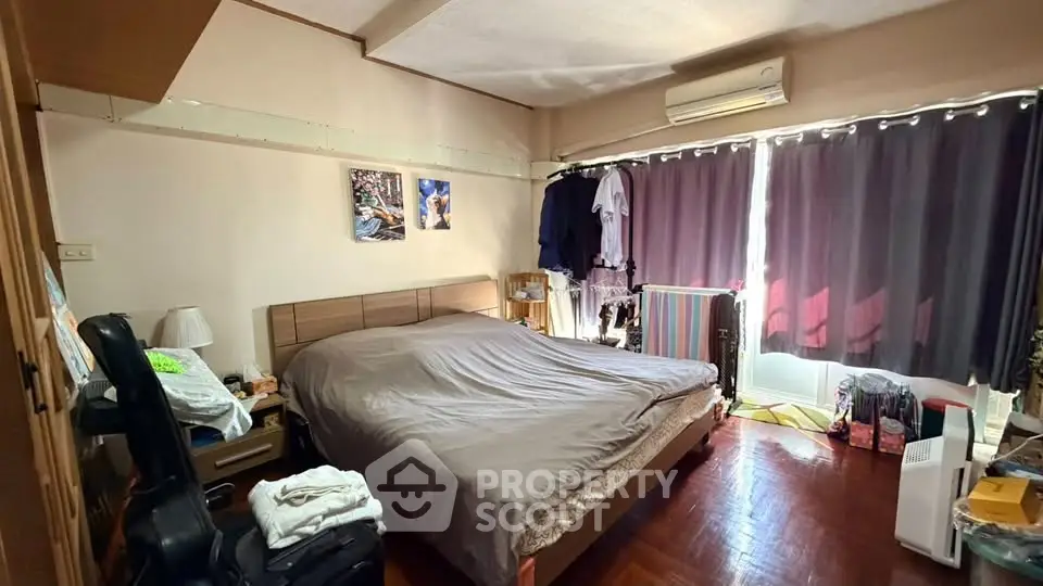 Cozy bedroom with large bed, air conditioning, and natural light from window.