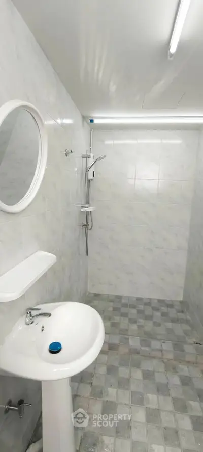 Modern minimalist bathroom with white fixtures and tiled walls, featuring a sleek shower area.