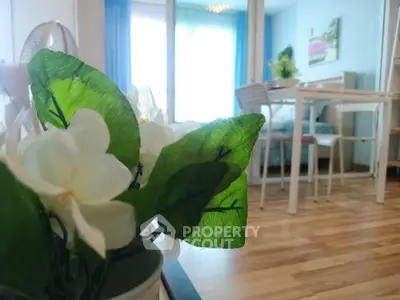 Charming living room with wooden flooring and elegant dining area, enhanced by natural light and floral decor.